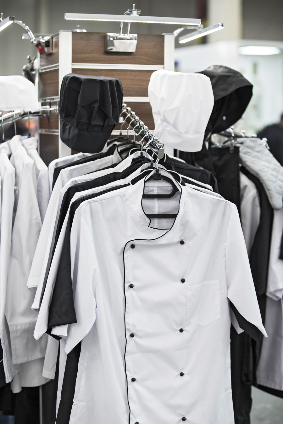 Cook uniform in a restaurant on a hanger, white and black uniforms, shirts and hats